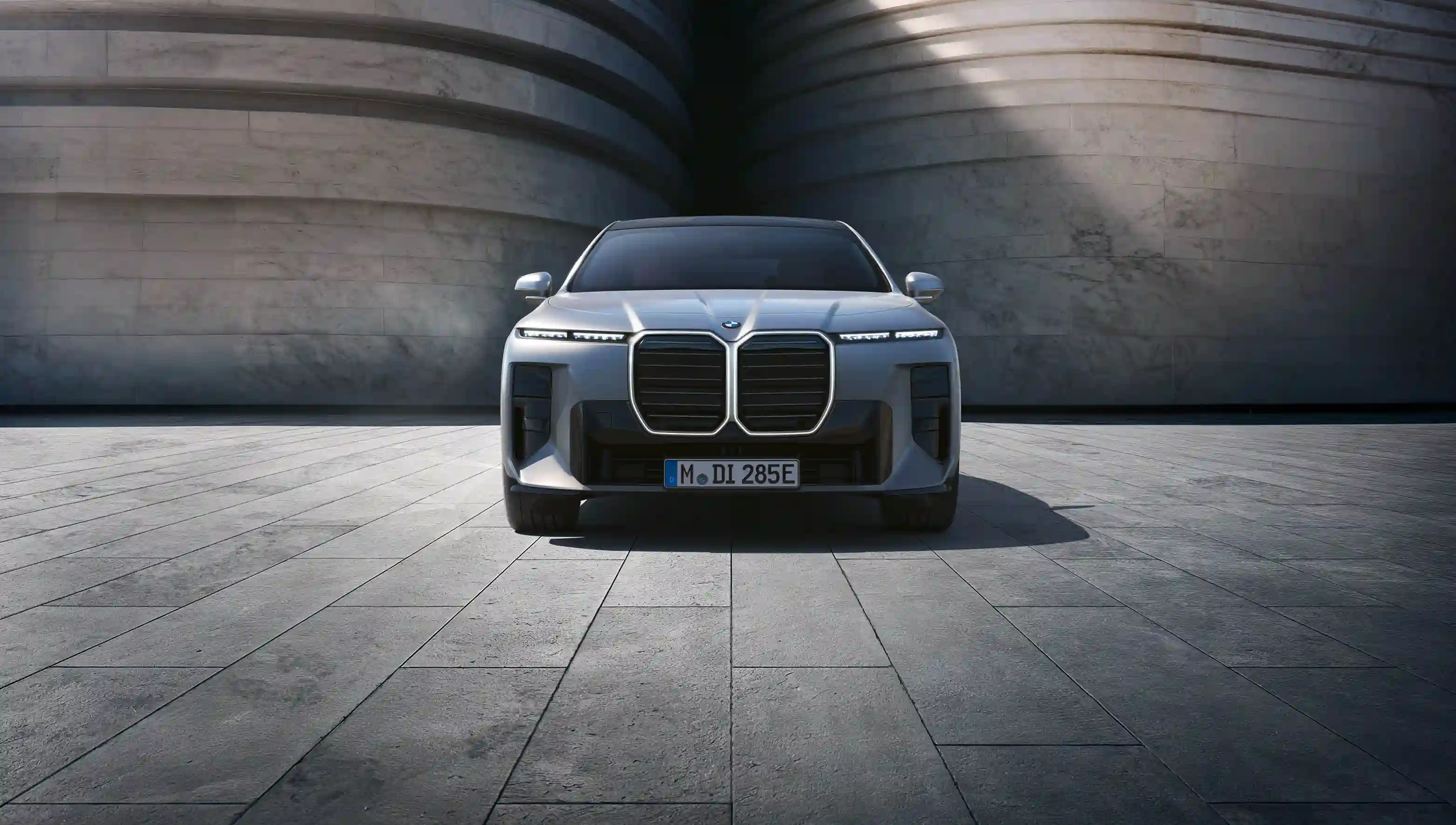 BMW i7 vor einer Steinwand in grau.