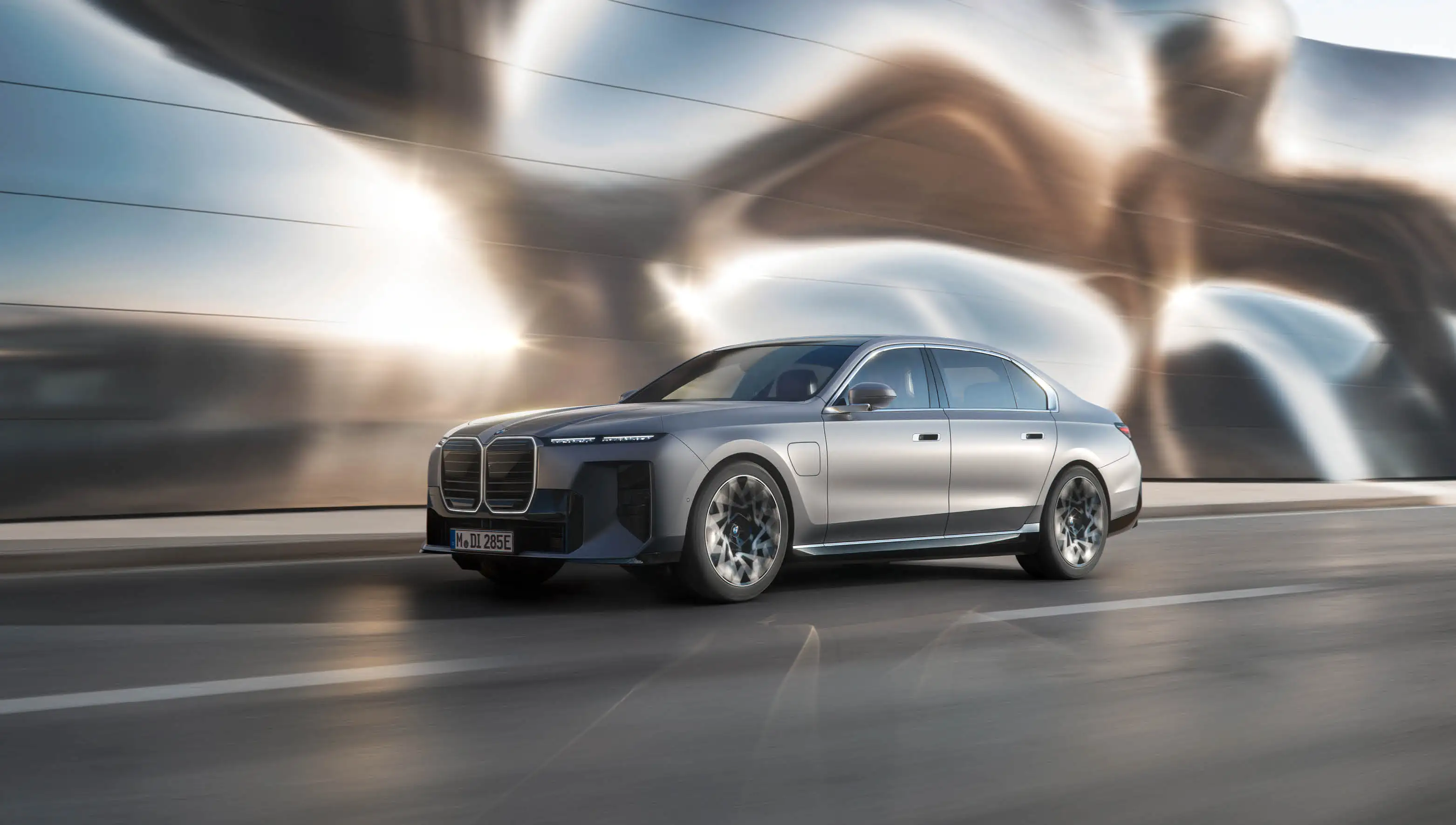 Silberner BMW i7 vor einer futuristischen Wand.