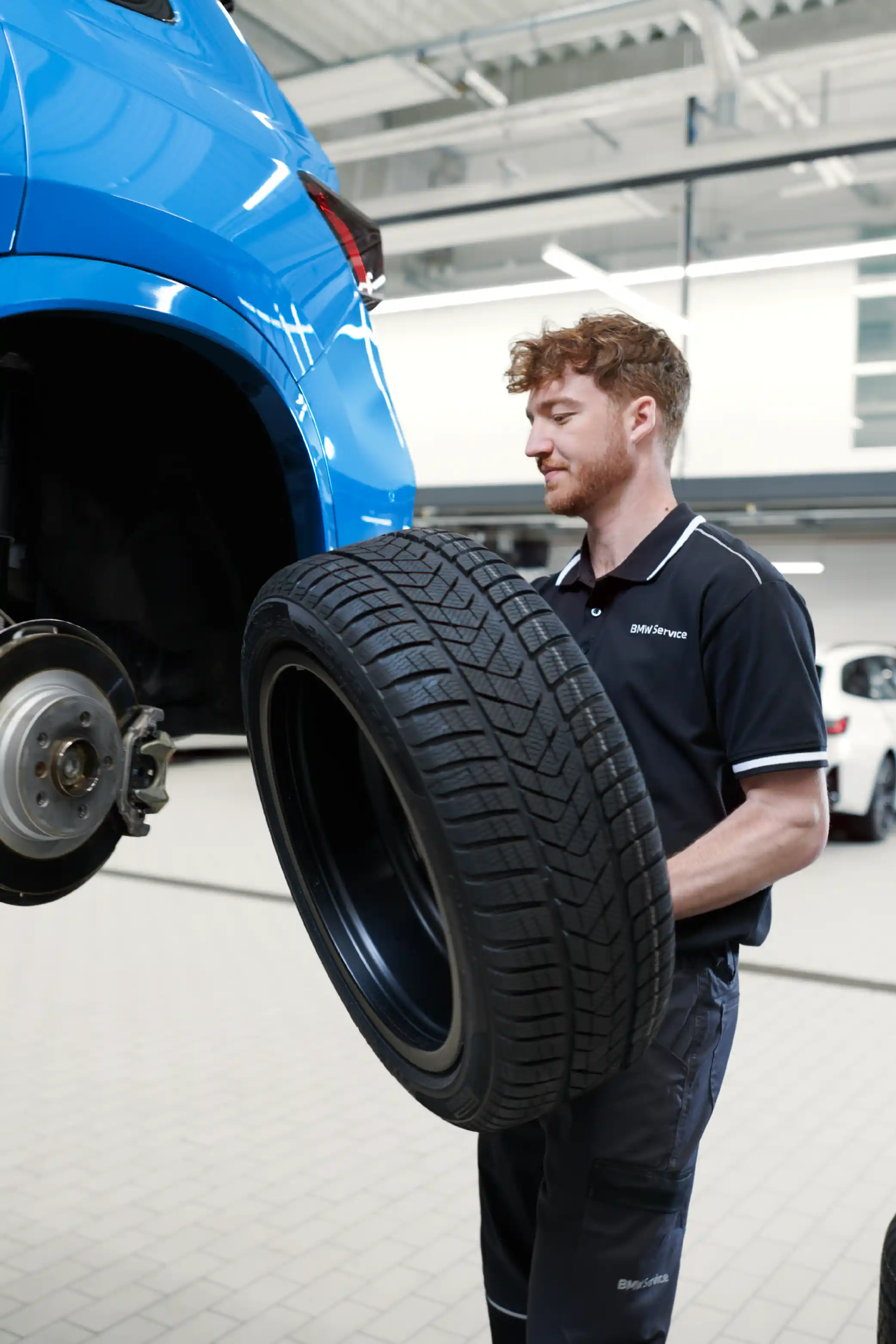 Junger Mann beim Reifenwechseln in einer BMW Werkstatt.