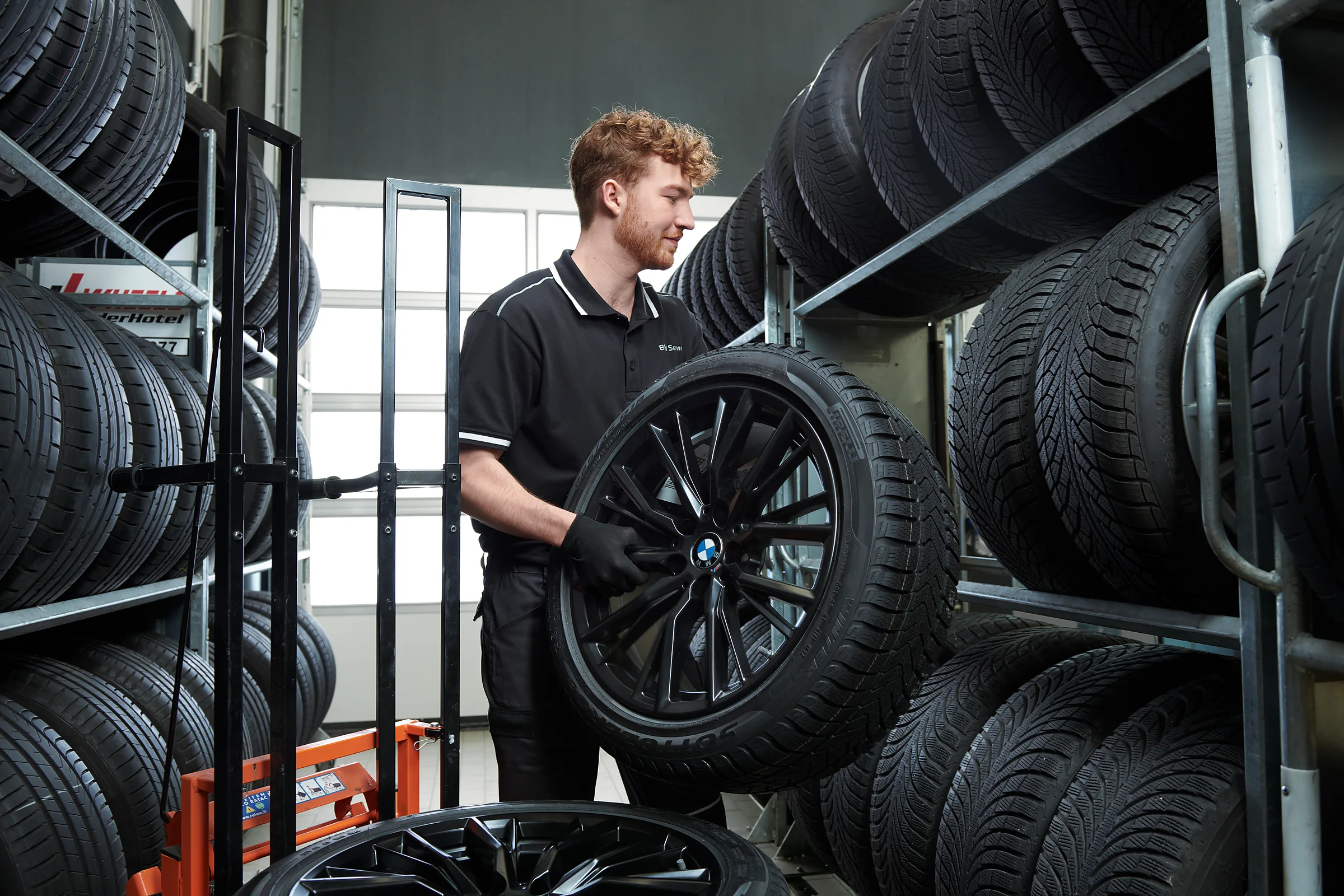 BMW Servicetechniker mit Kompletrad im Reifenlager – MOTORHEIMAT Wagner-Schwarz in Kirchseeon, Traunstein, Altenmarkt, Wasserburg und Oberhaching