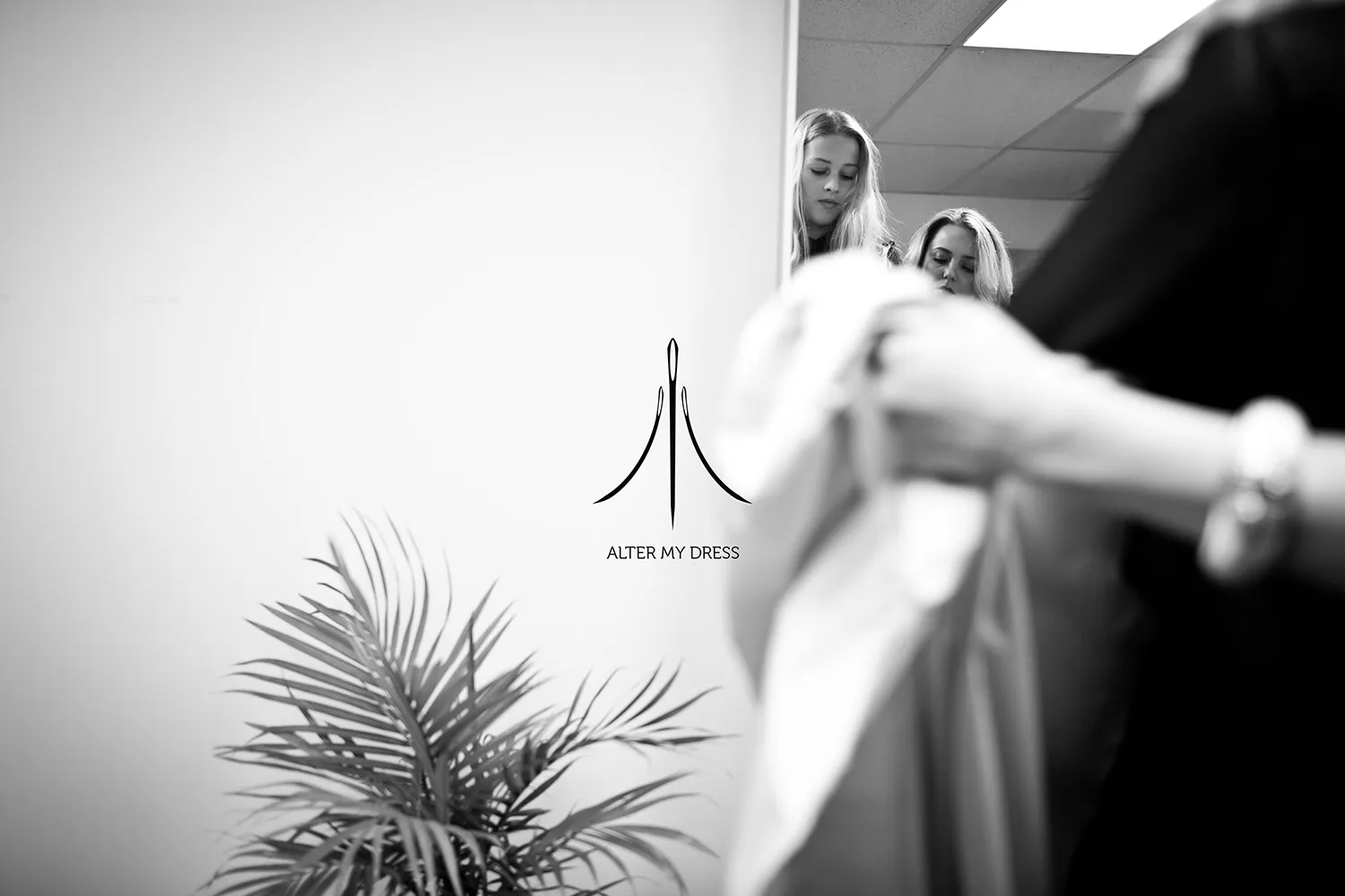 Alter My Dress logo on black and white background image of lead designer Priscilla with Philly bride in a wedding dress alterations fitting session