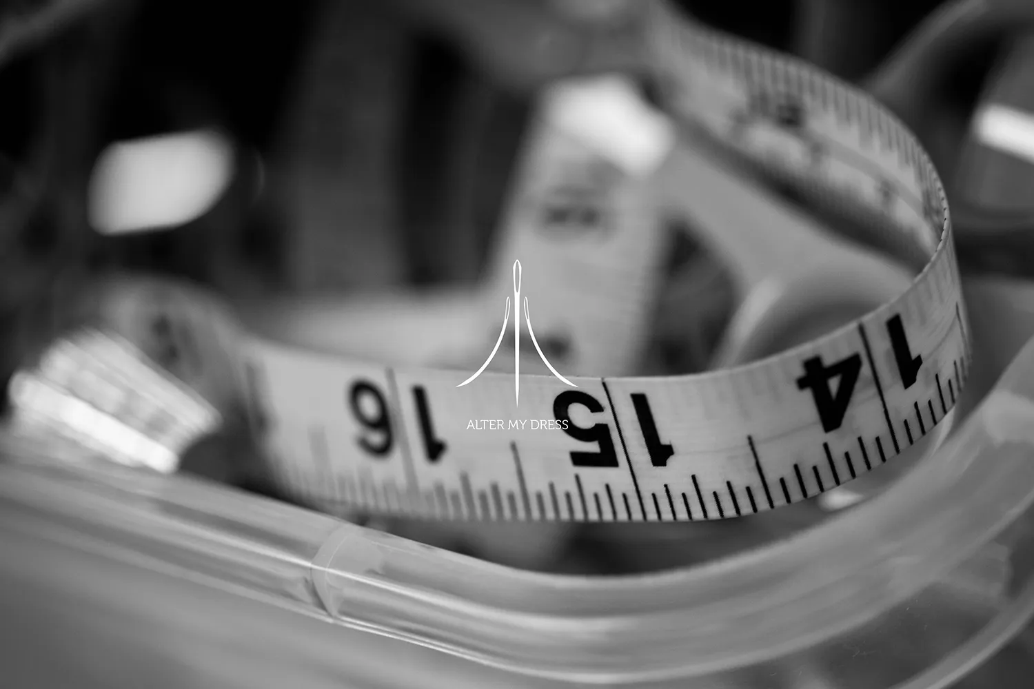 Alter My Dress logo on black and white background image of wedding dress alterations tape measure