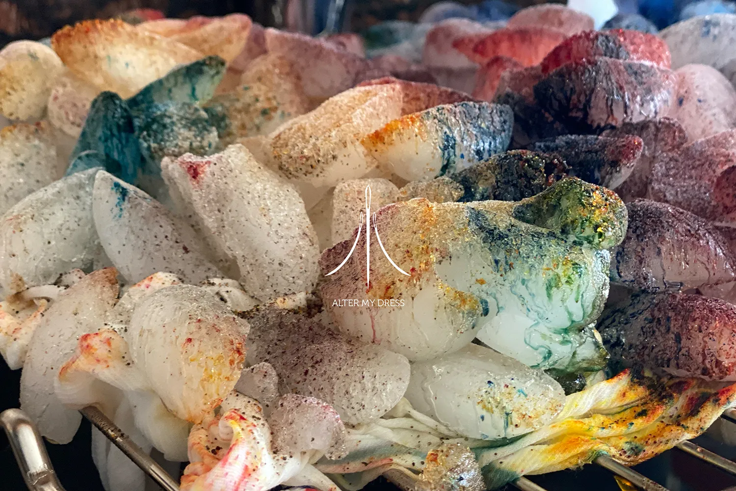 Seamstress adjusting the back of a white satin dress with pearl buttons on a woman.
