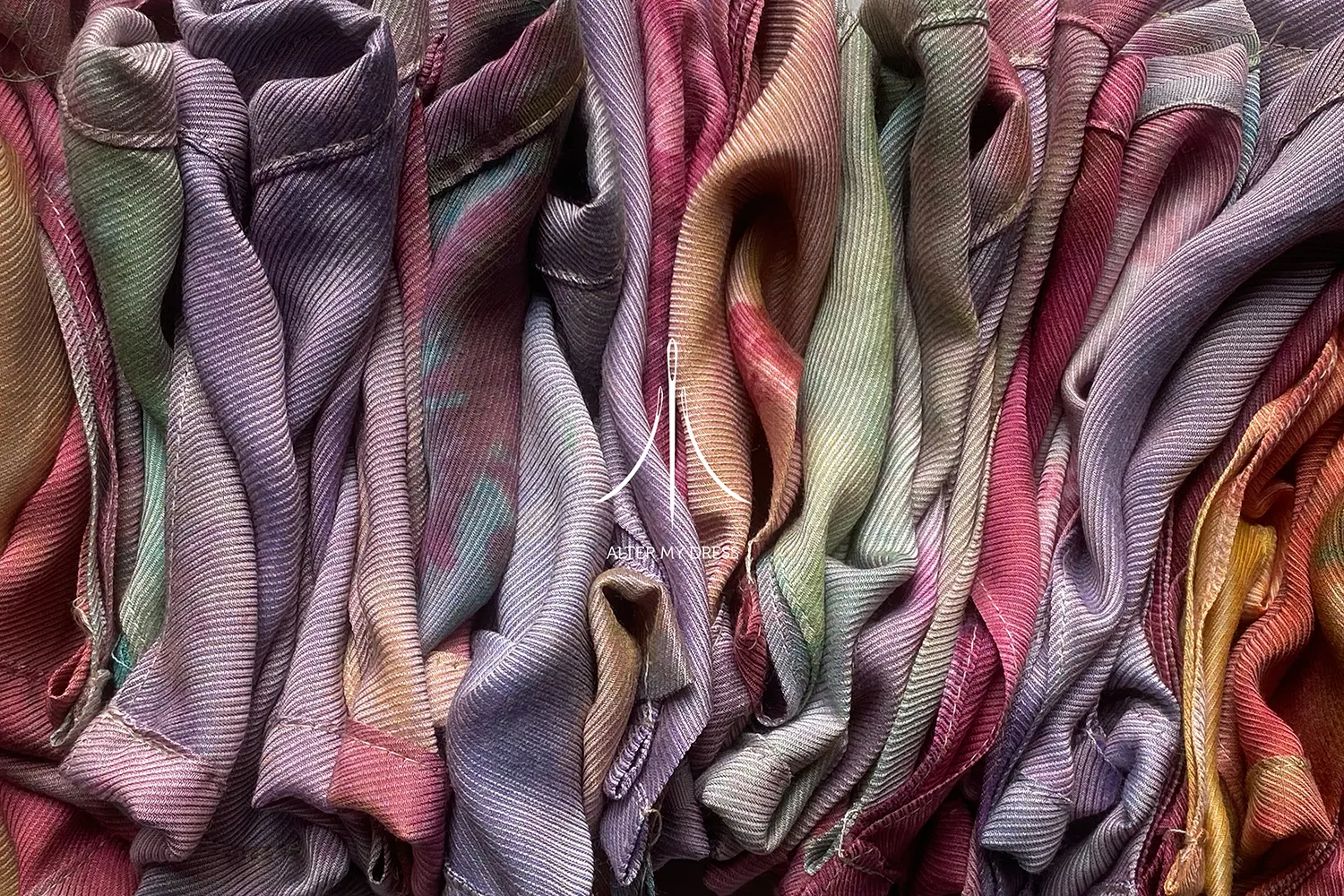Close-up of various colorful, ribbed fabric folds arranged closely together with a logo and the text 'ALTER MY DRESS' overlayed in the center.
