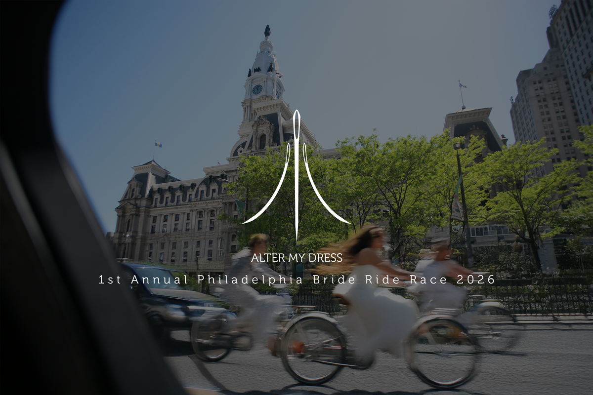 Three people dressed in wedding attire riding bicycles past Philadelphia City Hall on a sunny day.