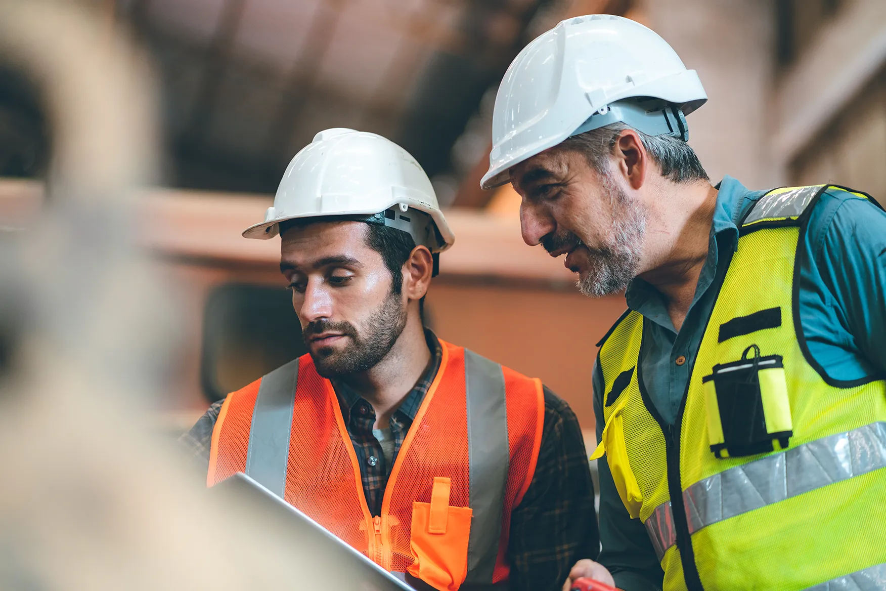 Two construction workers in hard hats discussing project details on site