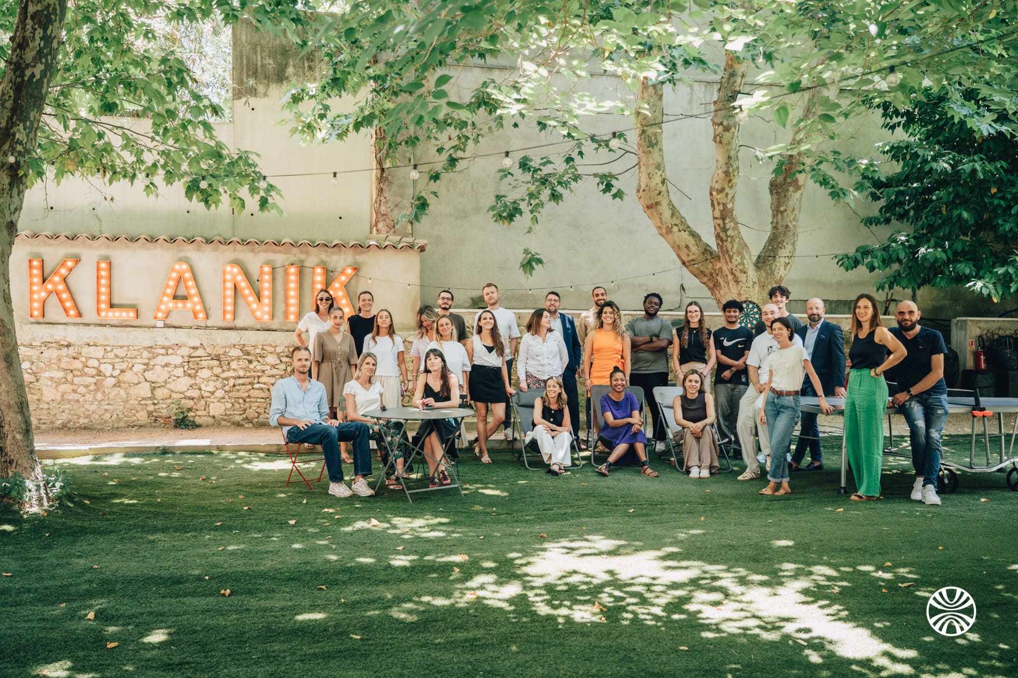 Équipe de consultant·es Klanik réunie devant une enseigne lumineuse lors d’une action d’engagement solidaire