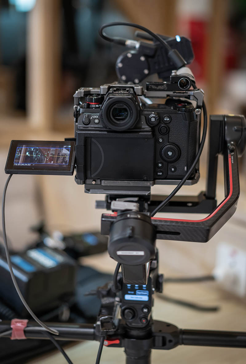 A camera mounted on a gimbal with a screen showing video footage, surrounded by equipment.