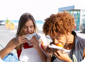 Young diverse couple having lunch with junk food