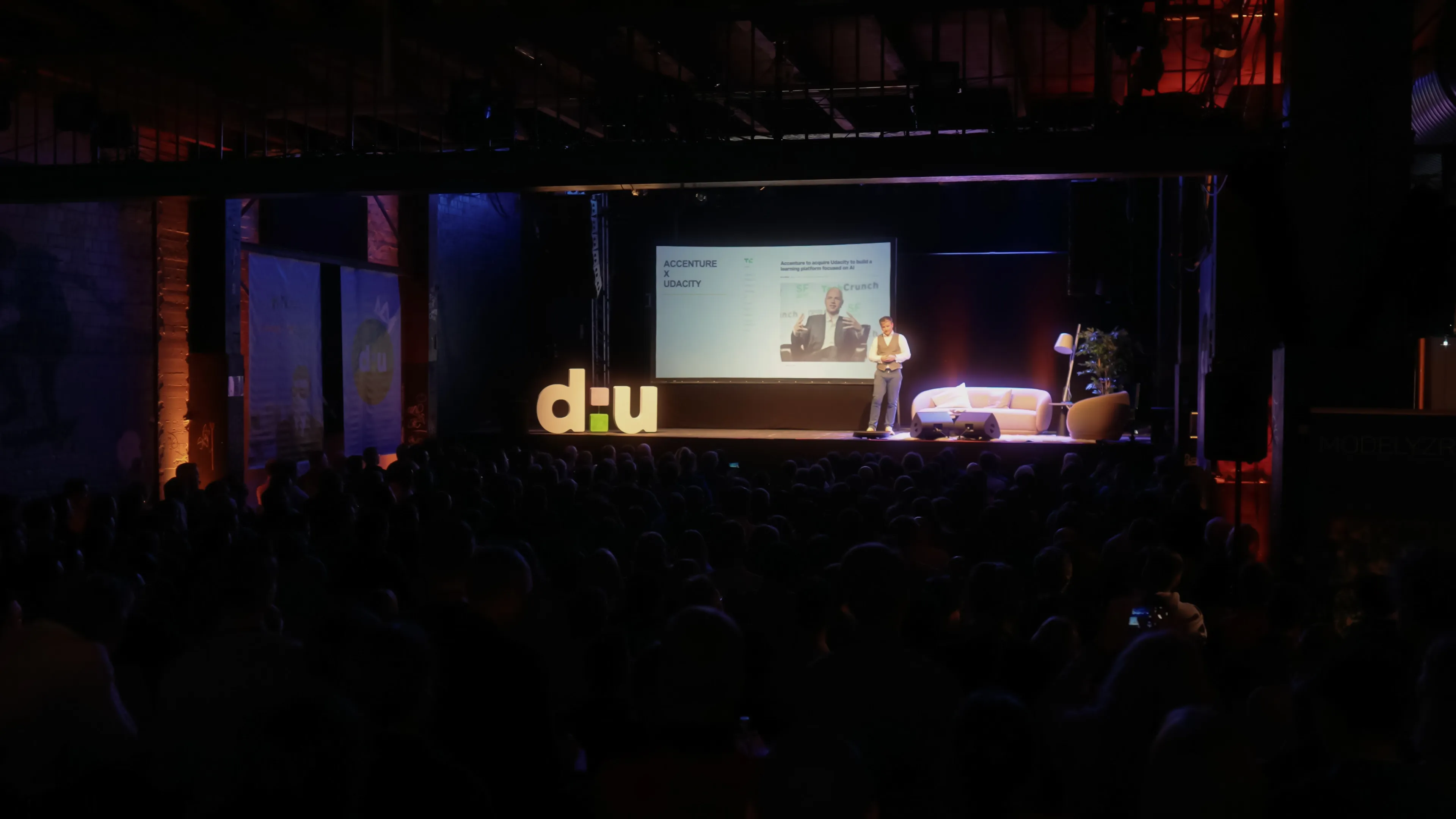 Bühne mit d:u-Logo vor dunklem Saal auf der data:unplugged 2024