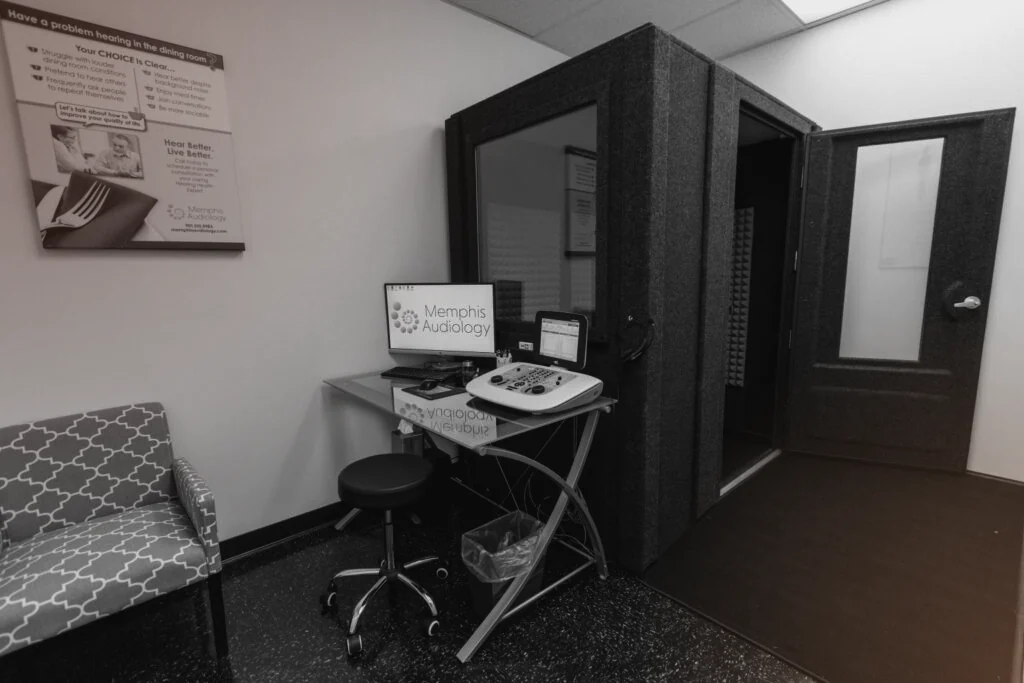 A WhisperRoom audiology booth in a hearing clinic, with the hearing test equipment on a desk just outside the booth window