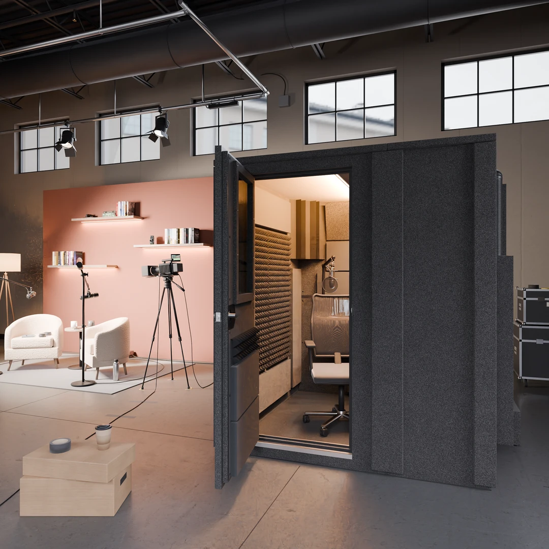 Creator Deluxe recording booth in an industrial content studio with a pink accent wall, white armchairs and a camera on a tripod