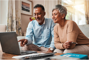 a couple on the couch looking at reports on a laptop