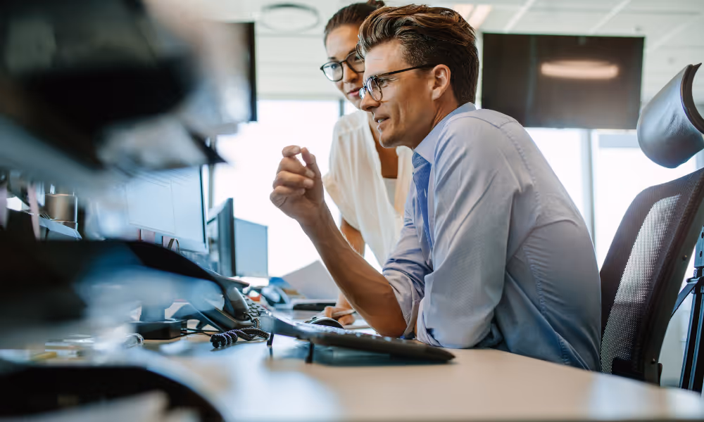Man looking at computer at his desk with colleague