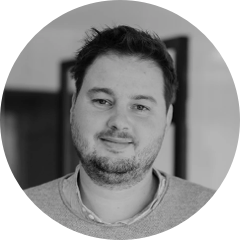 Philipp Schmidmaier in modernen Büro stehen mit Pulli, leicht lächelnd, Hände in den Hosentaschen