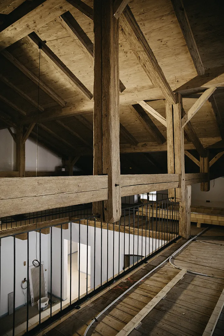 Historisches Gebäude mit sichtbaren Holzbalken im Dachstuhl; sorgfältig sanierte Konstruktion als Beispiel für Denkmalschutz im Bestand.