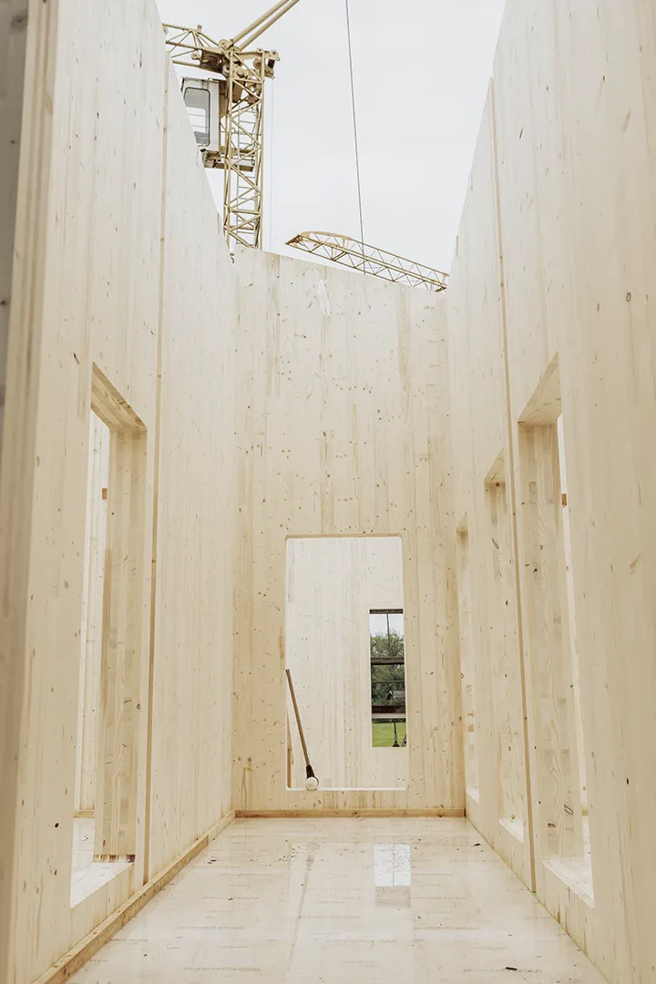 Ein moderner Holzbau mit hohen Wänden und großem Lichteinfall; deutliche Holzkonstruktion im Neubauprozess.