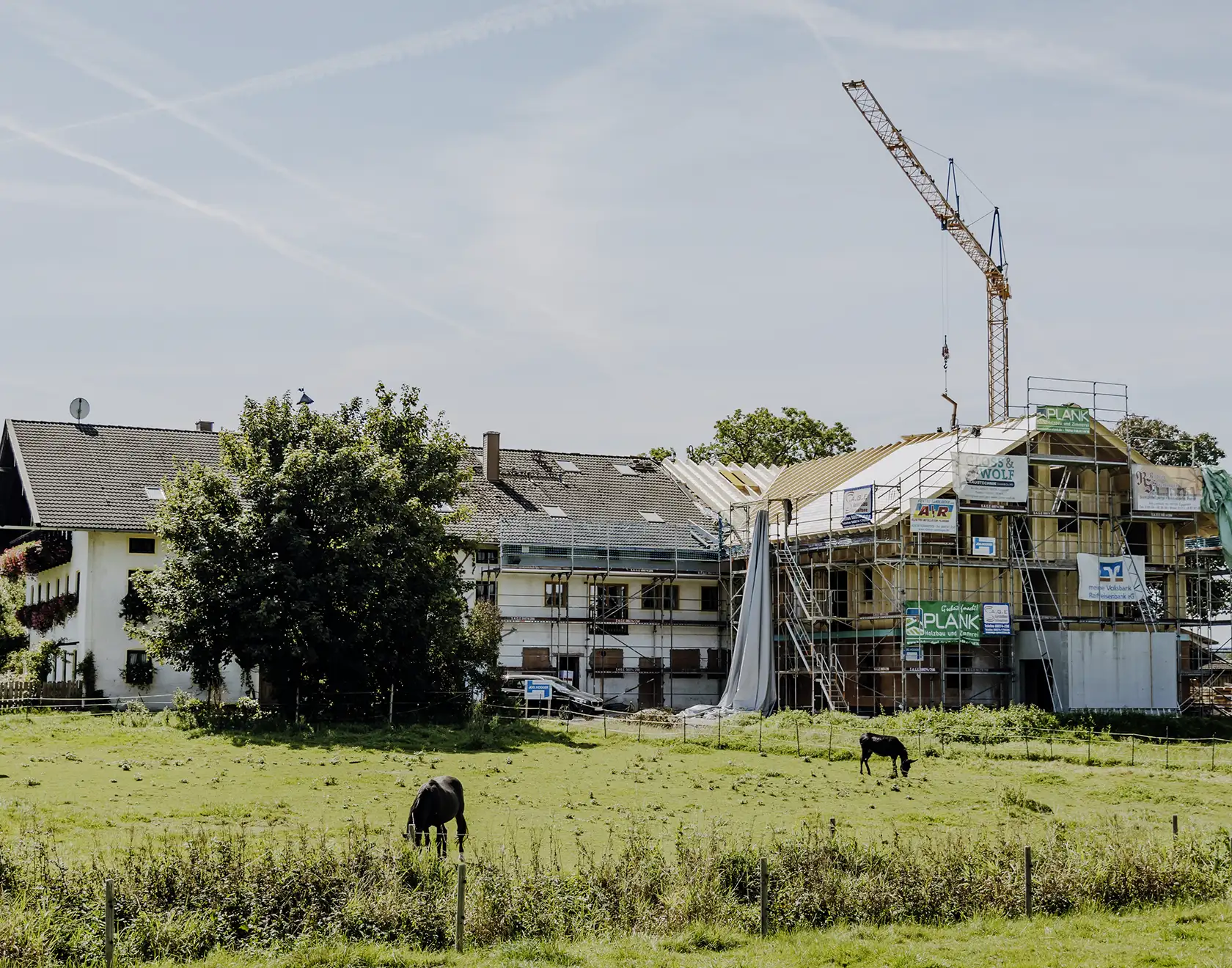Ein landwirtschaftliches Gebäude mit angebautem Wohnhaus wird mit einem Kran und Holzbaukonstruktionen modernisiert.