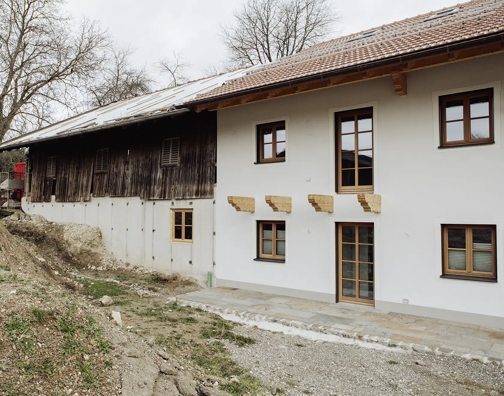 Ein traditionelles Wohnhaus mit Holz- und Putzfassade wird umgebaut; Bauarbeiten und neue Fensteröffnungen sind erkennbar.