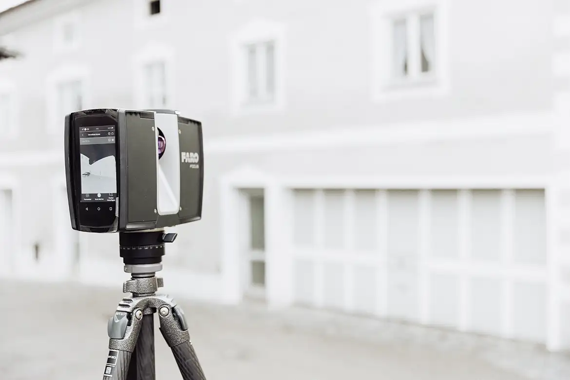 Ein 3D-Laserscanner der Marke FARO steht vor einem Gebäude und erfasst präzise Messdaten für das digitale Aufmaß.