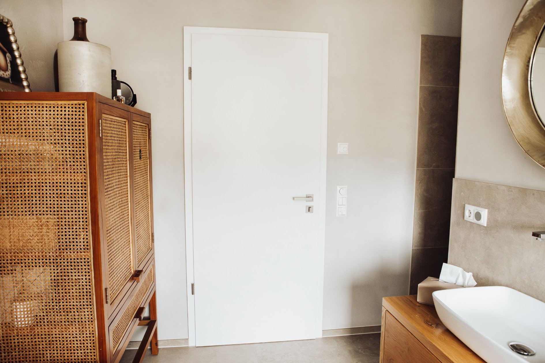 Weiß-matte Tür im Badezimmer mit Waschtisch und Naturmaterialien