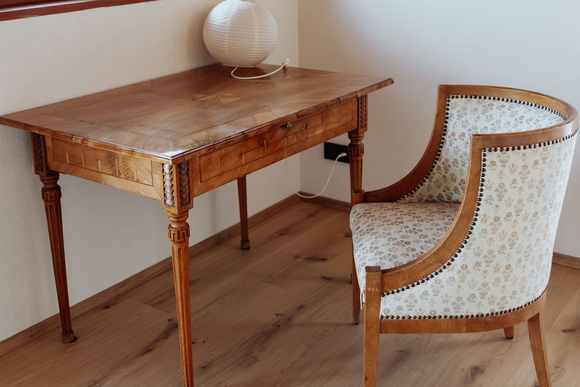 Detailaufnahme einer Leseecke mit Holztisch und Sessel auf hell geöltem Eichenparkett mit natürlicher Sortierung.