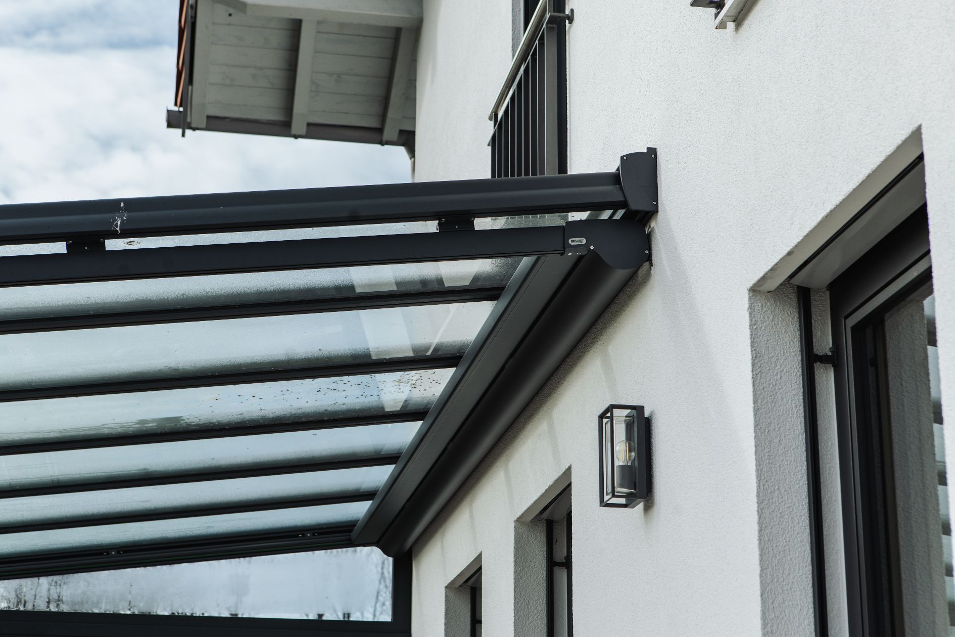 Detailansicht eines modernen Terrassendachs aus Glas und Aluminium mit integrierter Unterglasmarkise.