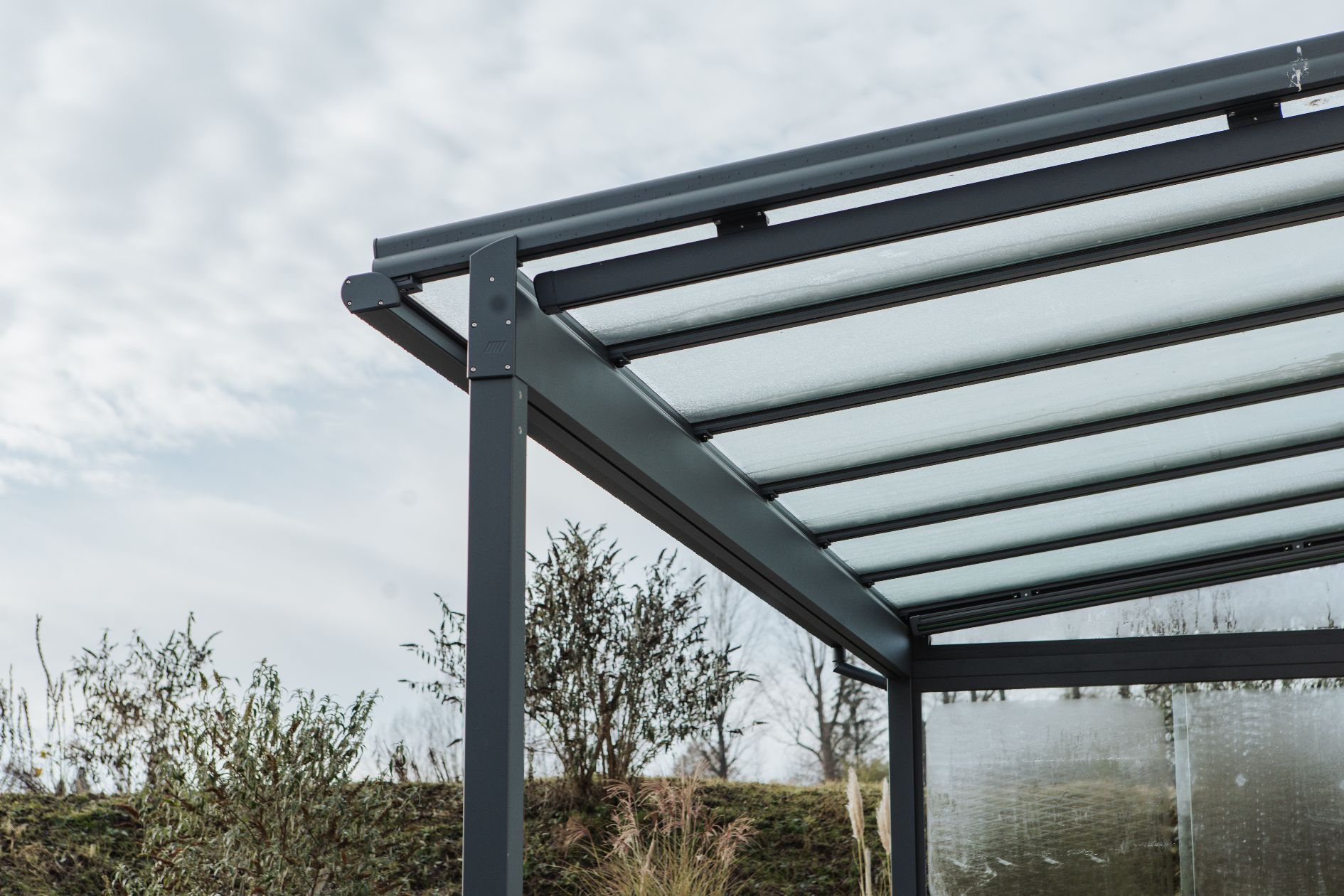 Detailansicht des Terrassendachs mit integrierter Unterglasmarkise und Glaseindeckung auf anthrazitfarbenem Aluminiumgestell. 