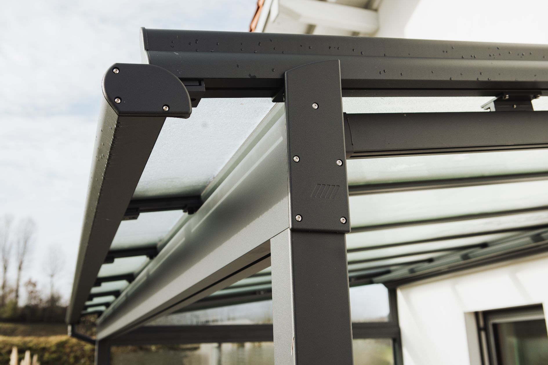 Detailaufnahme vonanthrazitfarbenen Aluminiumkonstruktion mit integrierter Unterglasmarkise und Glaseindeckung.