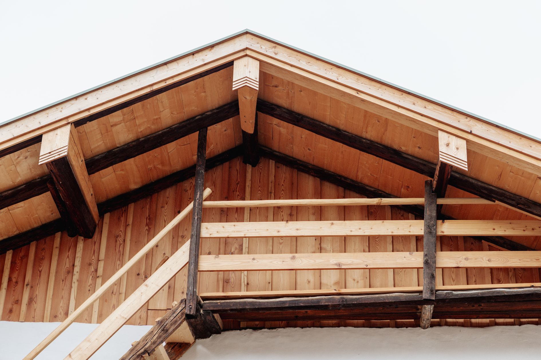 Detailansicht des sanierten Dachbereichs mit neuer Holzschalung aus Lärche und erhaltenen historischen Balken am Brendlhaus in Bad Reichenhall.