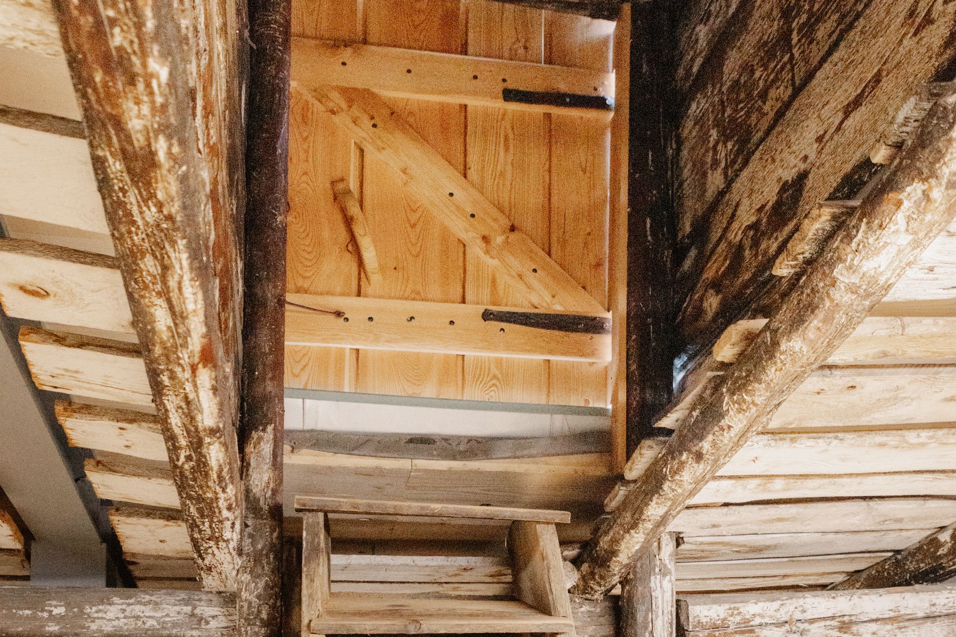 Holztreppe im Dachgeschoss des Brendlhauses, alte Stufen führen durch einen schmalen Durchbruch in den Dachraum.