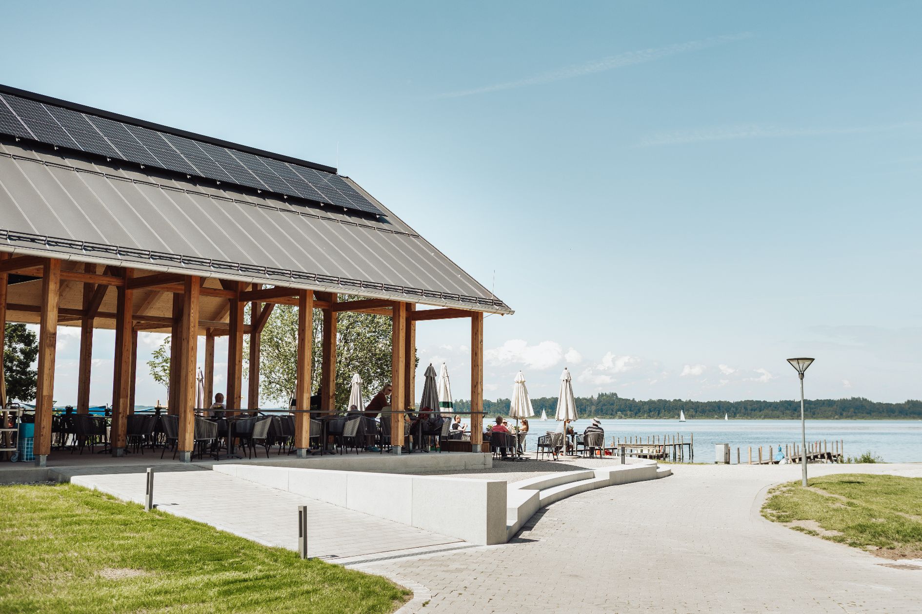 Terrasse des Strandbads Felden mit Holzbau und Blick auf den Chiemsee.