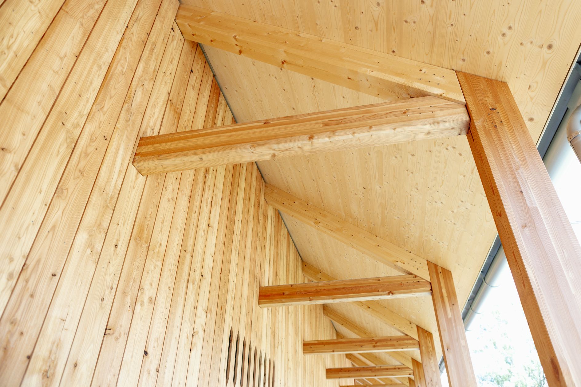 Detailansicht der Holzfassade, sichtbaren Dachkonstruktion und Brettsperrholzdecke.