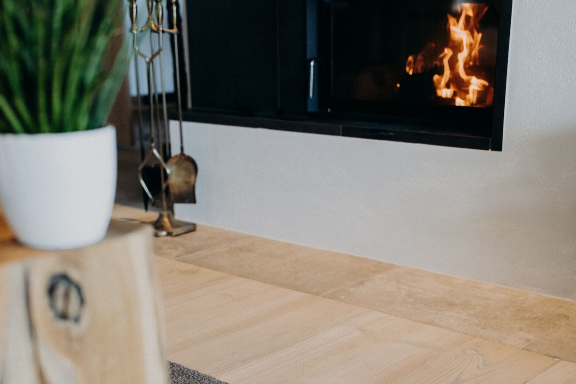 Detailaufnahme von Lärchendielen und Naturstein vor dem Kamin im Wohnbereich.