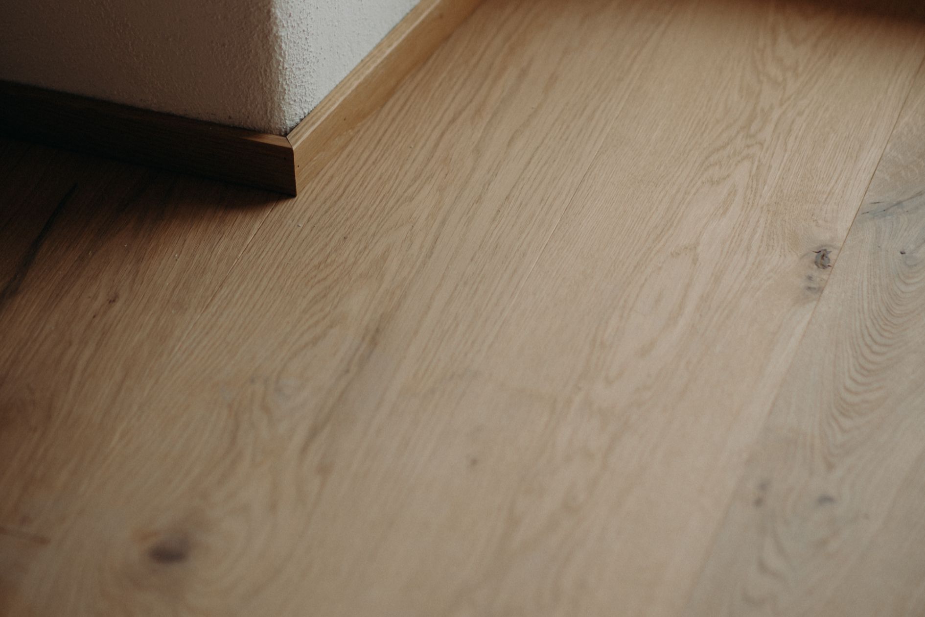 Detailaufnahme einer geölten Eichen-Landhausdiele mit passender Sockelleiste in einem sanierten Altbau.