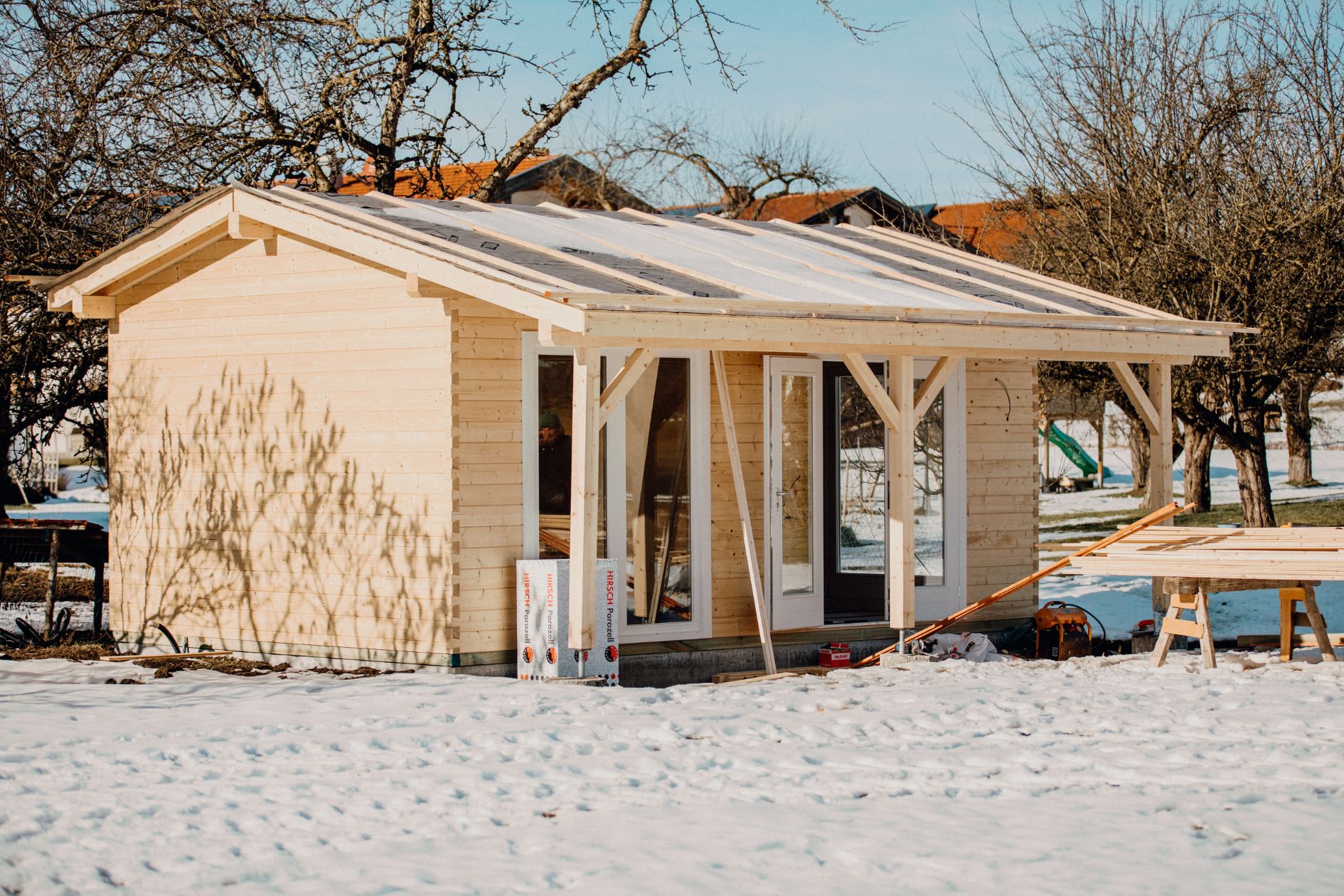 Saunahaus im Rohbau mit Holzfassade und Winterlandschaft.
