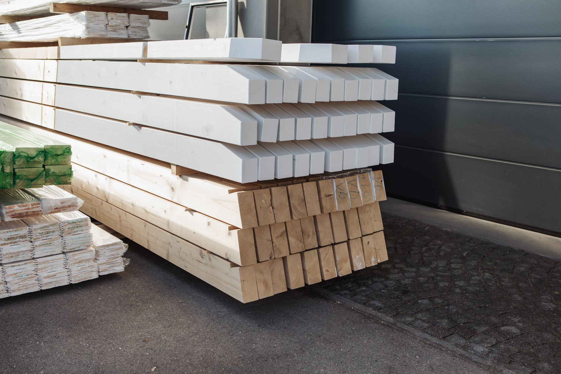 Gestapelte Holzbalken, teils weiß gestrichen, teils naturbelassen.