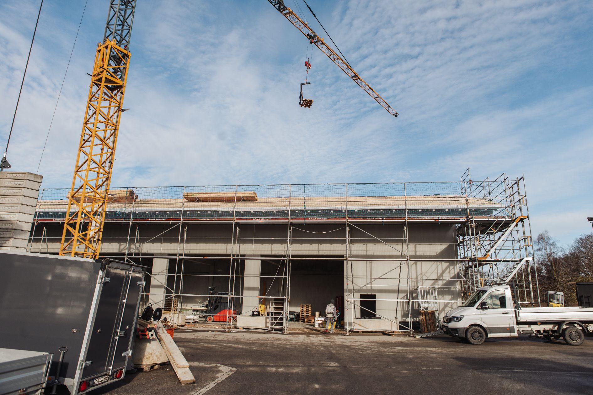 Baustelle einer Halle mit Kran und Gerüst.