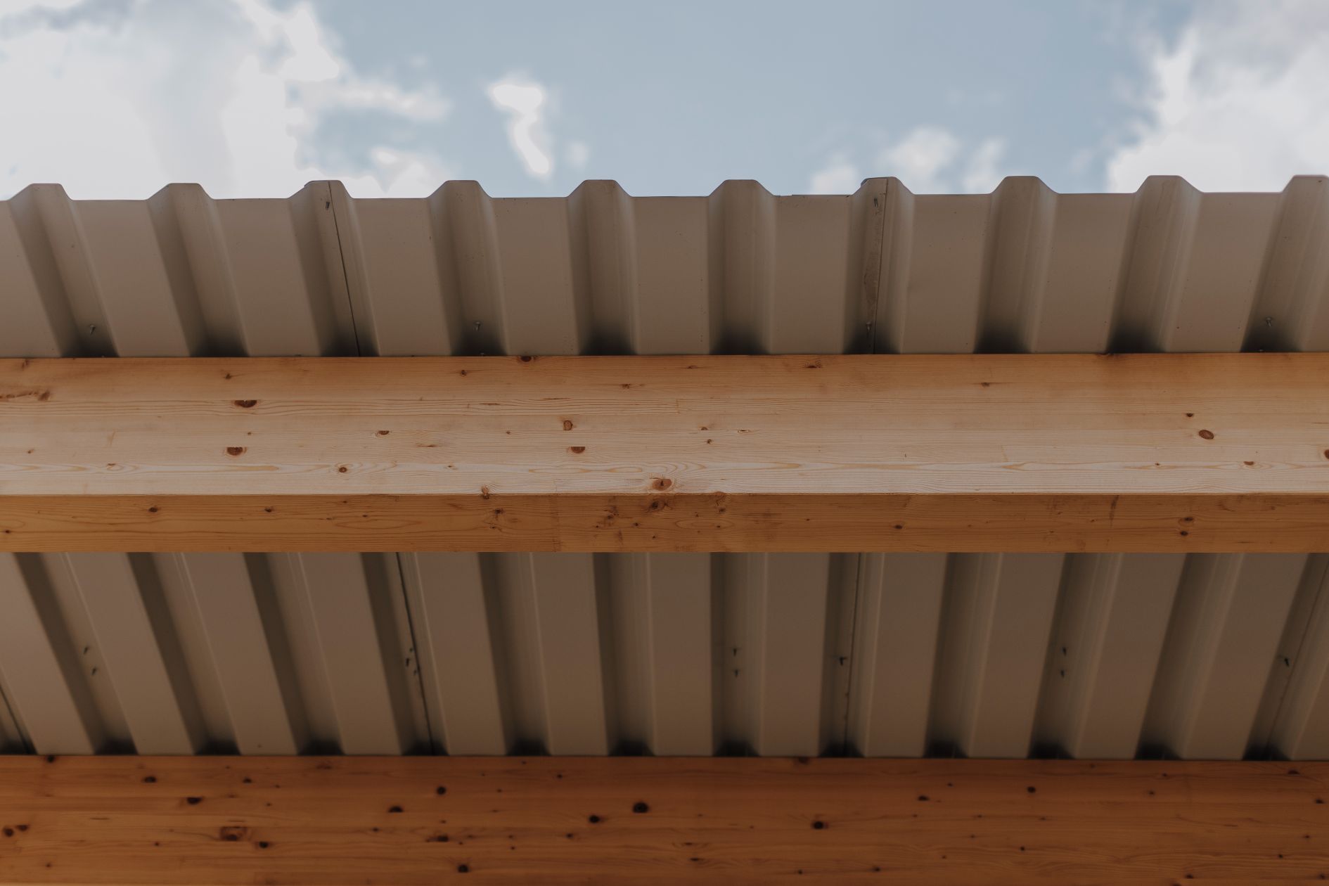 Detailaufnahme eines Brettschichtholzträgers mit Blechdach.