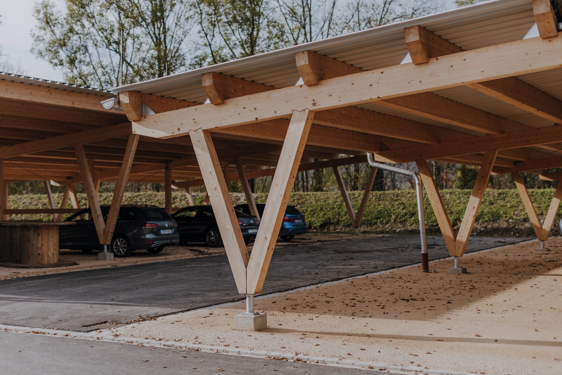Überdachter Holz-Carport mit schrägen Stützen.