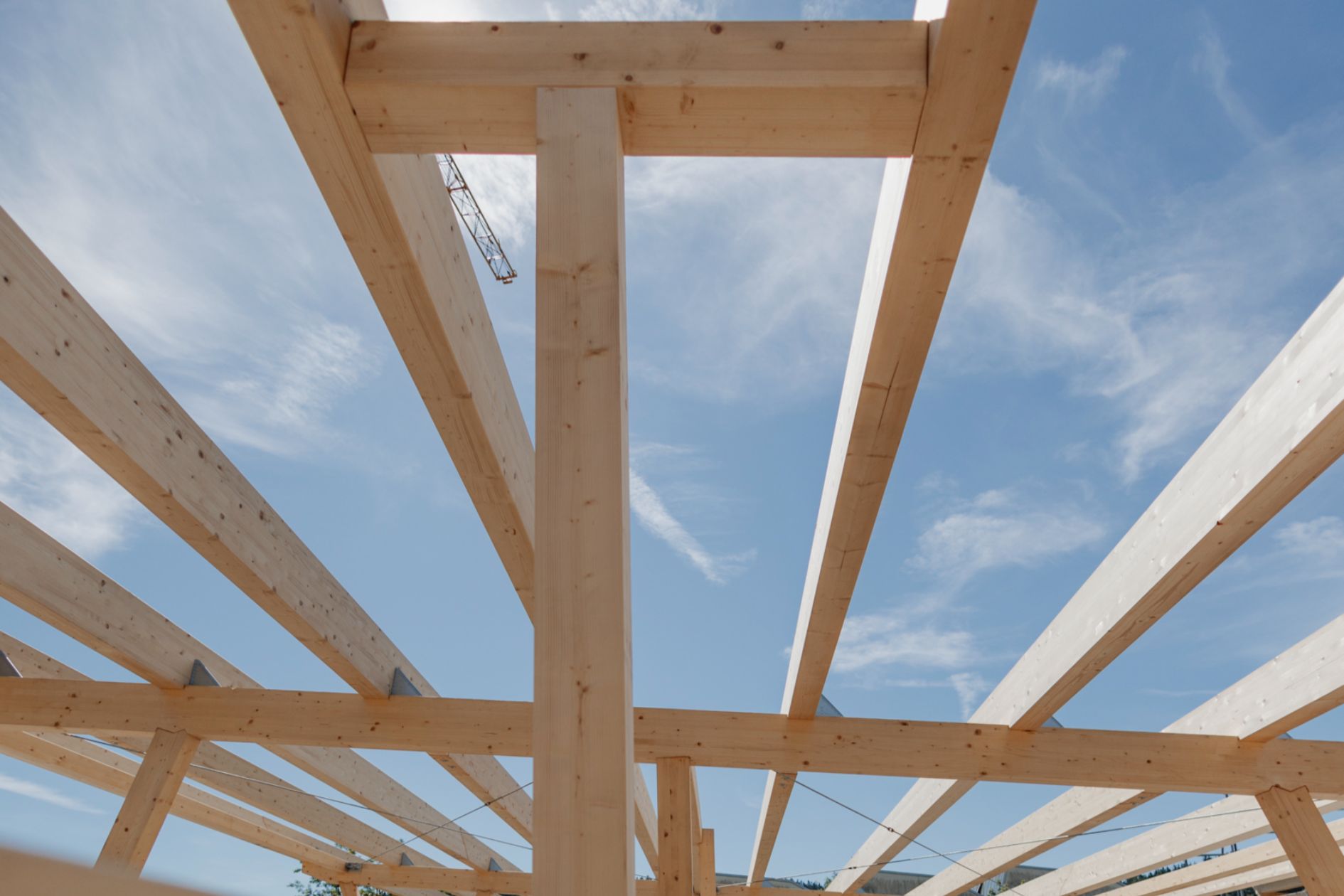 Blick durch Holzbalken eines Carports in den Himmel.