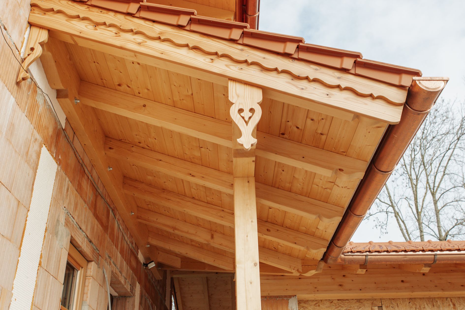 Vordachkonstruktion aus massivem Holz mit sichtbaren Zierleisten.