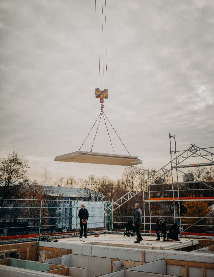 Montage einer CLT-Deckenplatte per Kran auf der Baustelle.