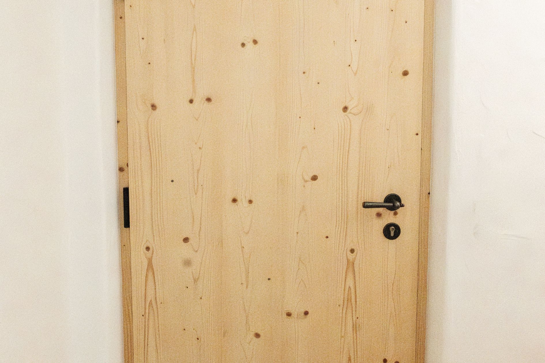 Massivholztür aus naturbelassenem Holz mit sichtbarer Maserung, eingebaut in eine weiße Wand.