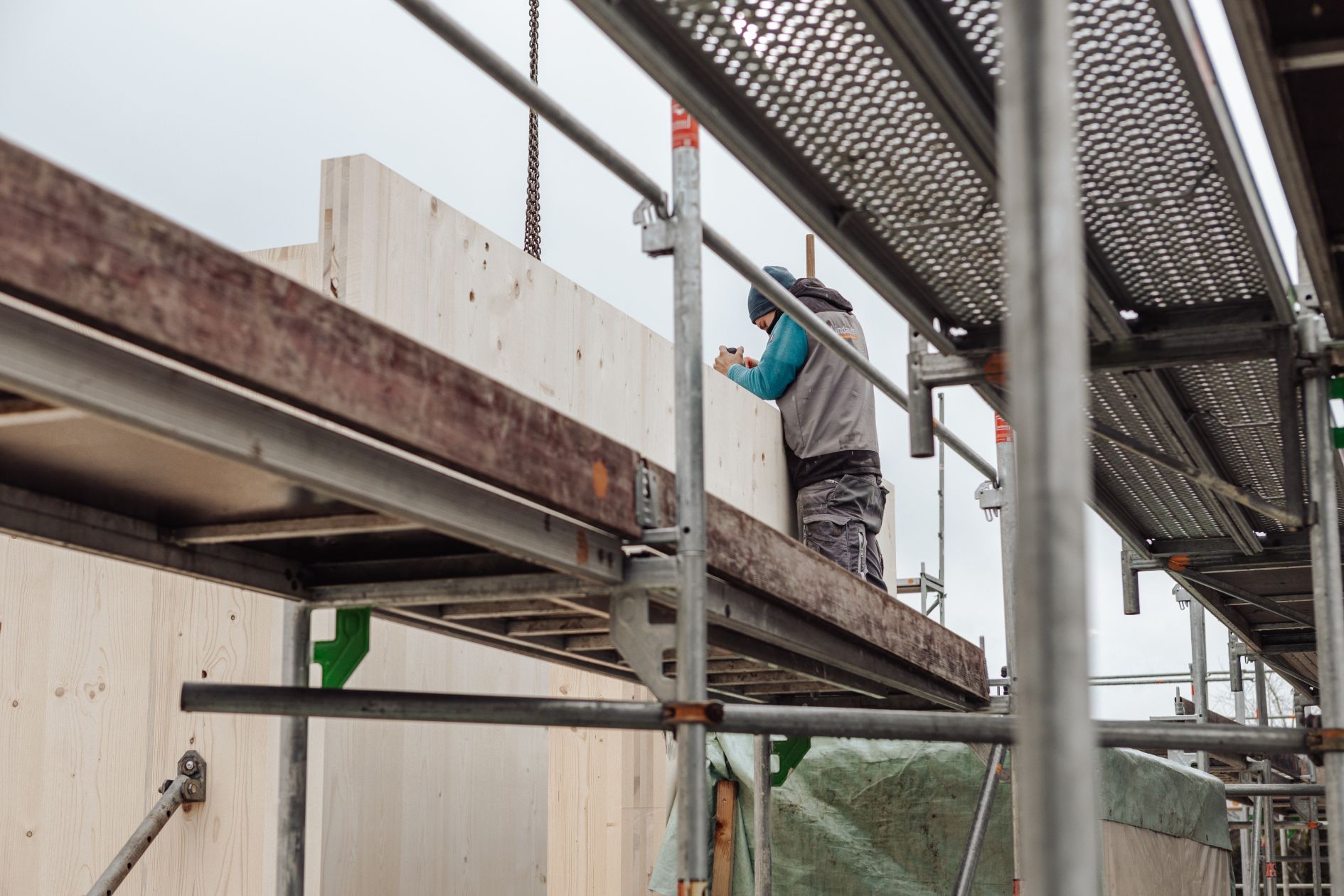 Handwerker positionieren vorgefertigte Holzmodule mit Fensteröffnungen.