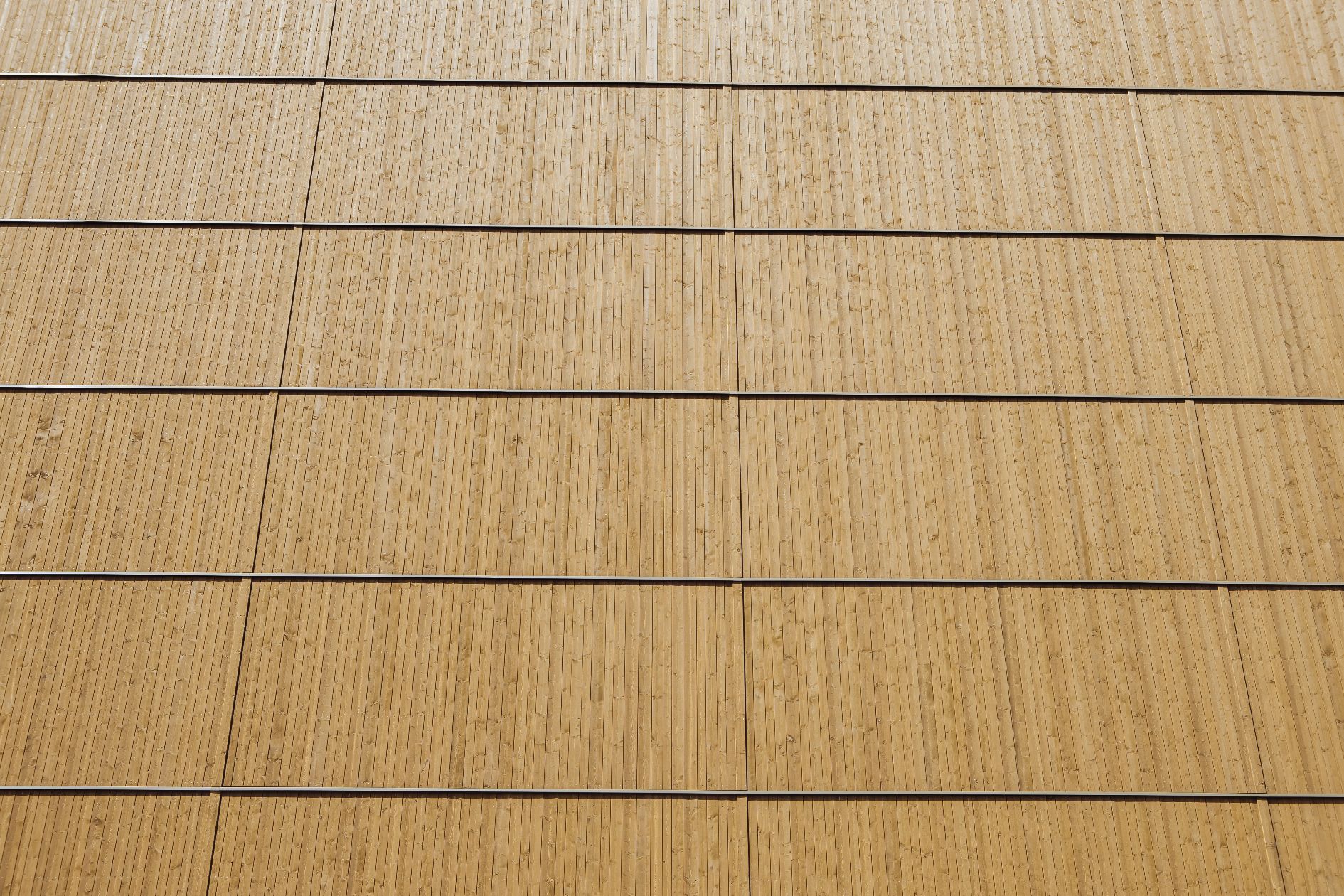 Nahaufnahme einer Holzfassade mit vertikaler Profilierung und gleichmäßiger Plattenanordnung