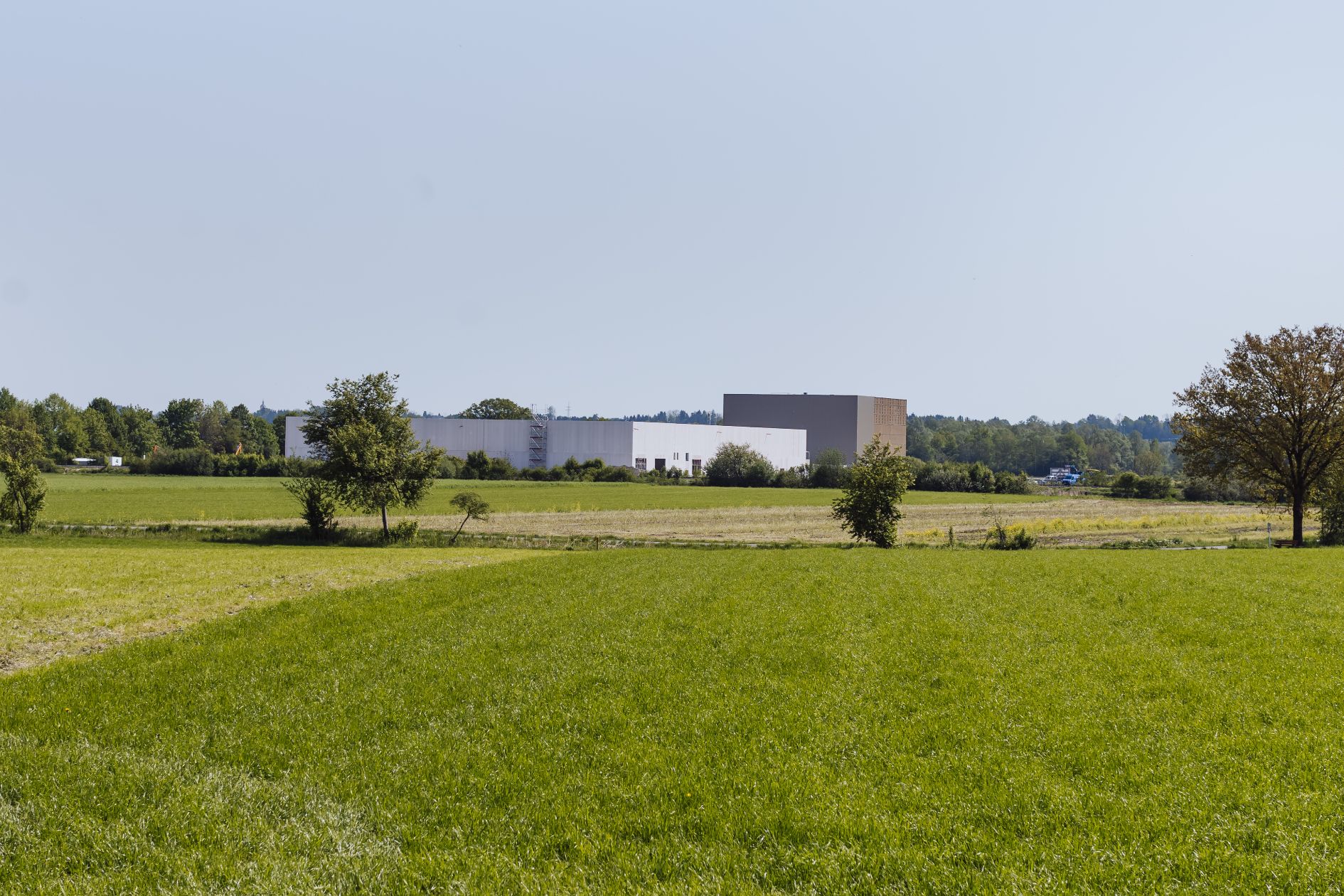 Weitaufnahme einer Industriehalle mit Holzfassade in grüner Landschaft