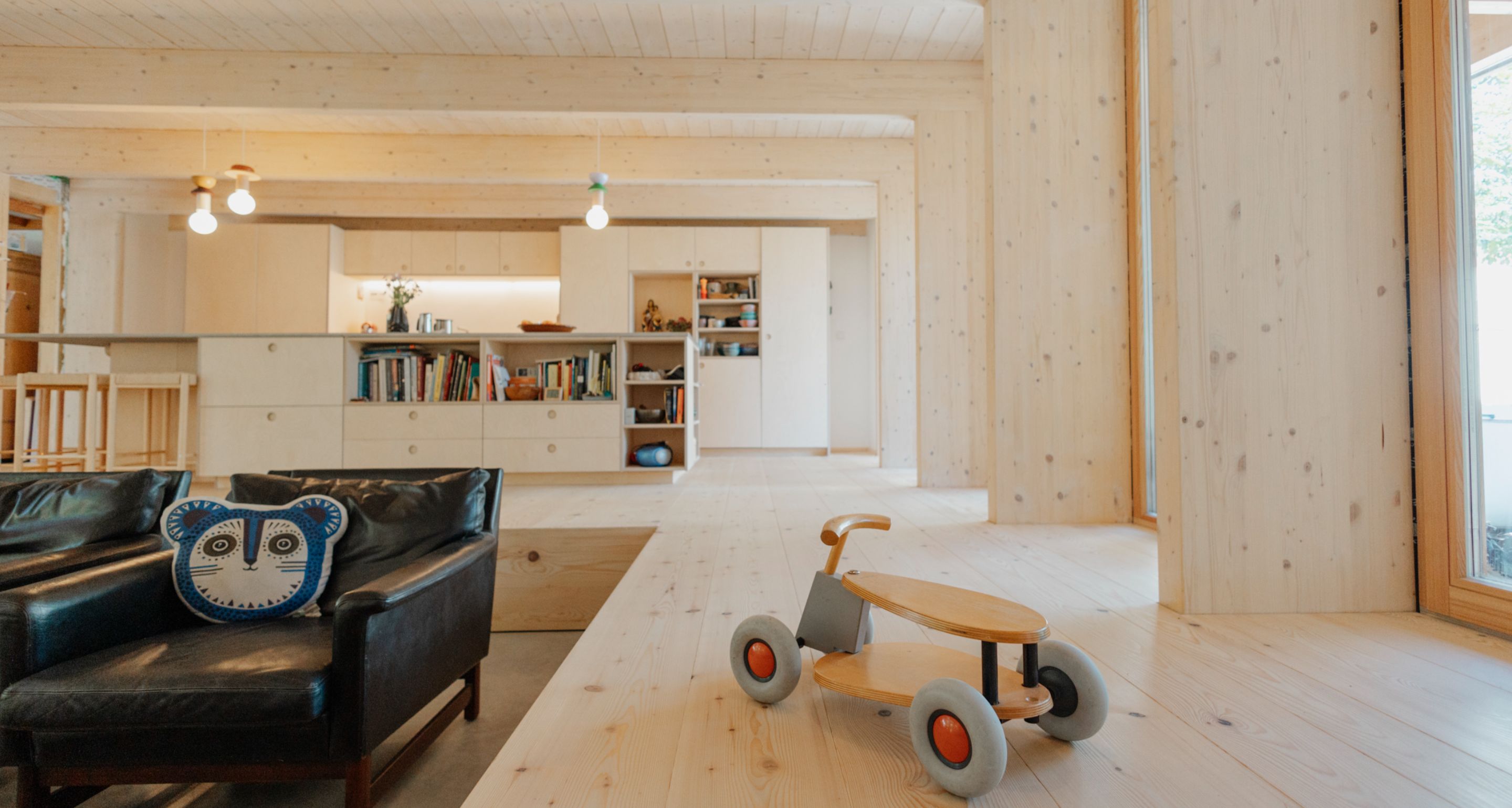 Helles Wohnzimmer mit raumlanger Tannendiele, sichtbarem Estrich und moderner Holzeinrichtung.