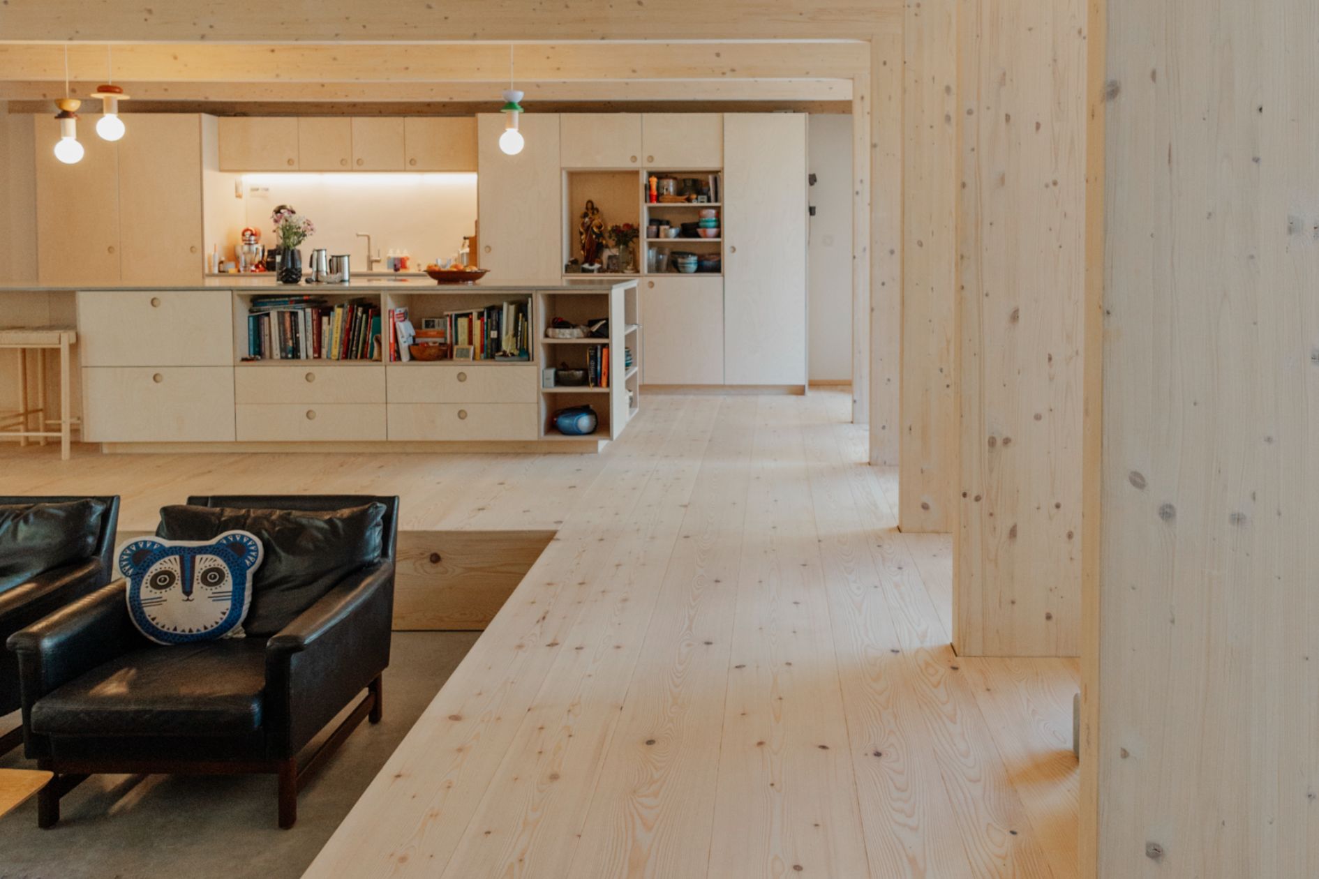 Helles Wohnzimmer mit raumlanger Tannendiele, sichtbarem Estrich und moderner Holzeinrichtung.