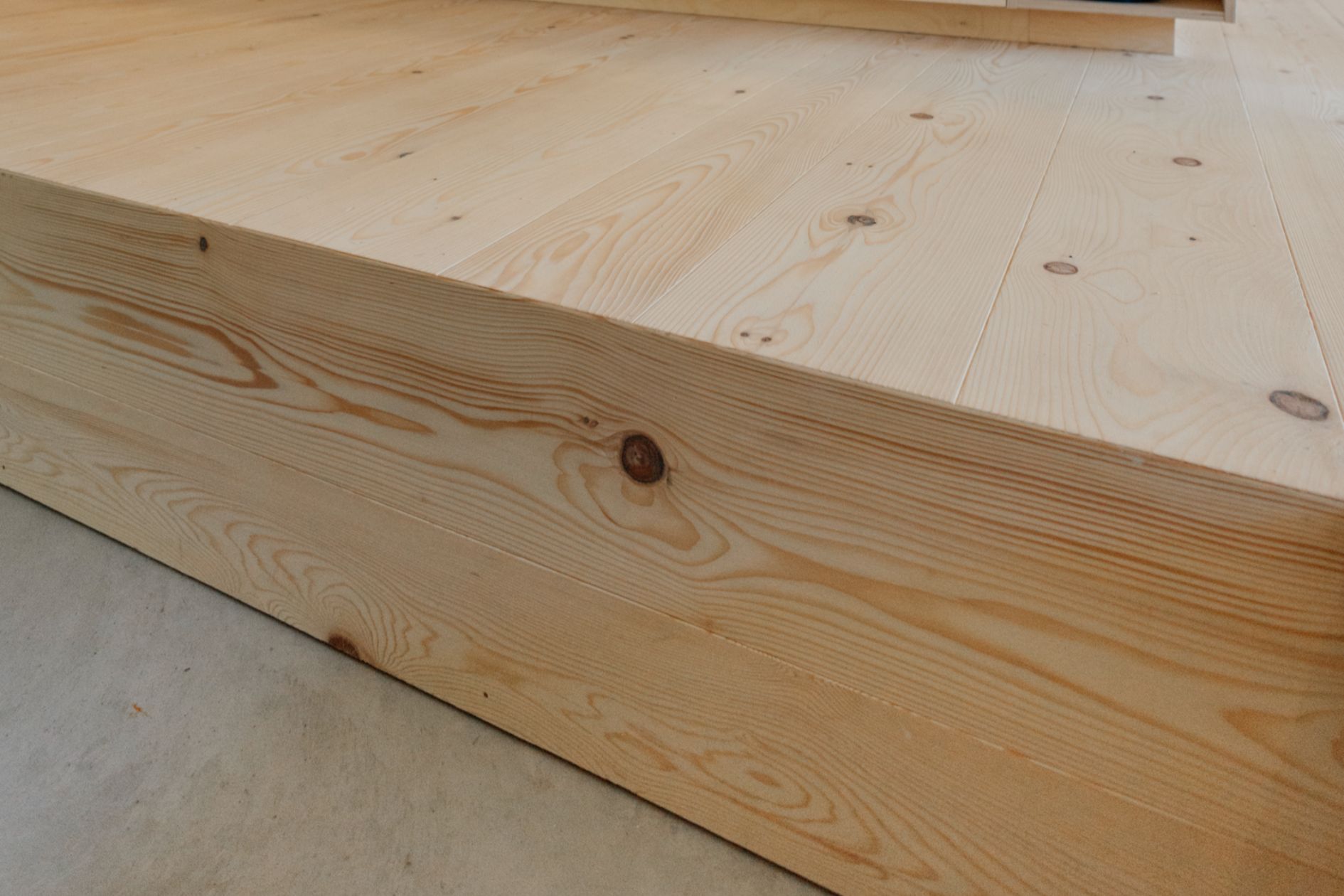 Detailaufnahme von einer Stufe mit raumlanger Tannendiele und Sichtestrich.
